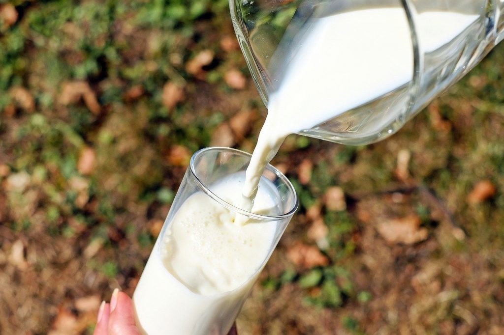 Milk pours from a jug into a glass